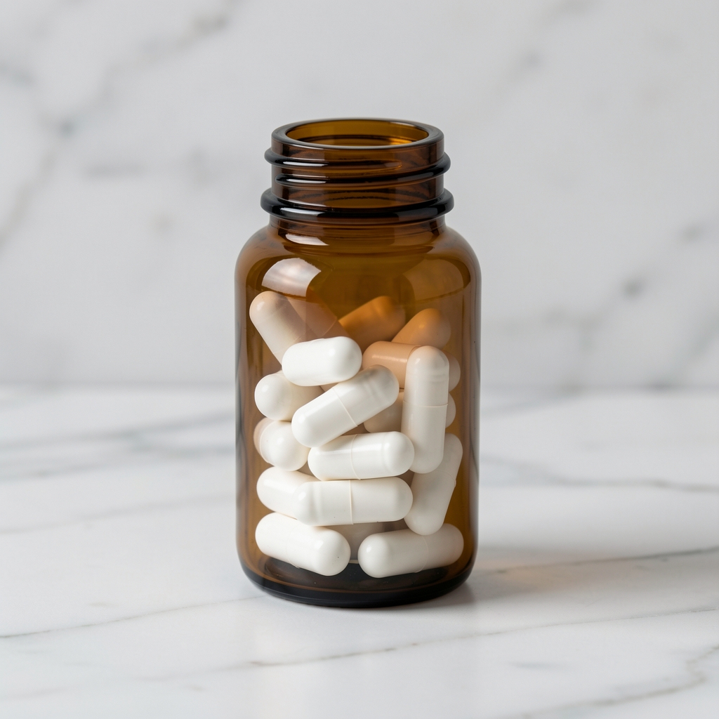 Brown glass supplement bottle with white capsules arranged on white marble surface, editorial product photography with soft directional lighting